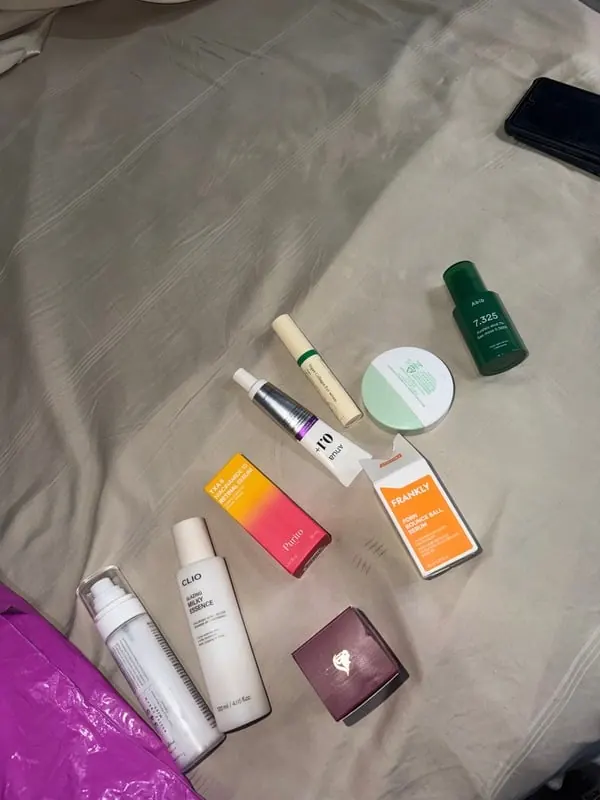 Skincare flat lay of serums, creams and a compact on a linen sheet